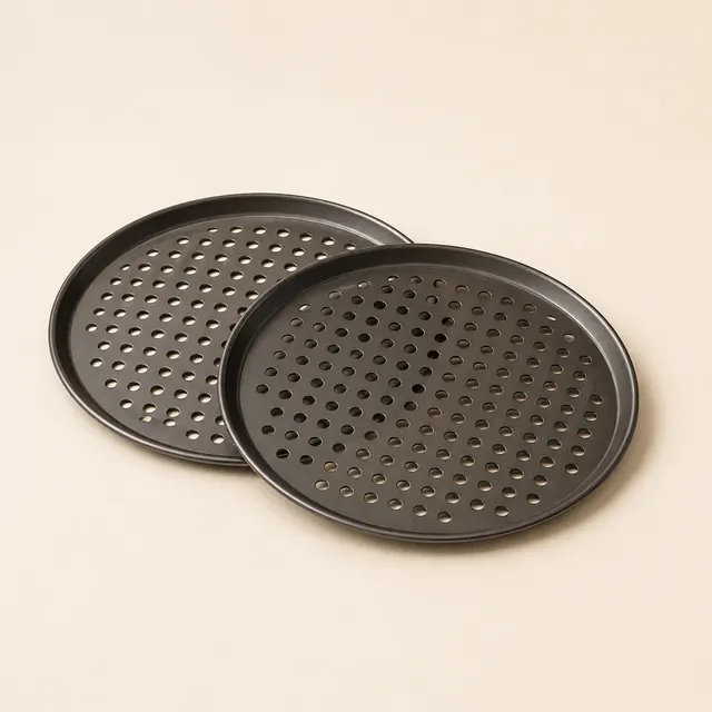 Two round perforated pizza pans, holes visible across the cooking surface